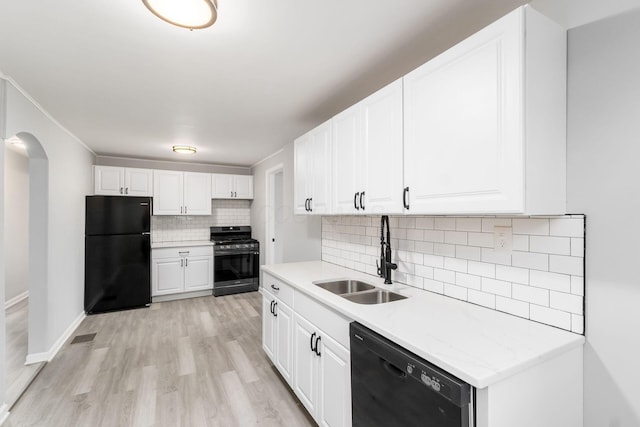 kitchen featuring sink, white cabinetry, black appliances, light wood-type flooring, and backsplash