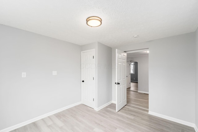 spare room with a textured ceiling and light wood-type flooring