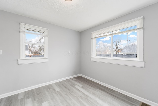 unfurnished room featuring a healthy amount of sunlight, a textured ceiling, and light wood-type flooring