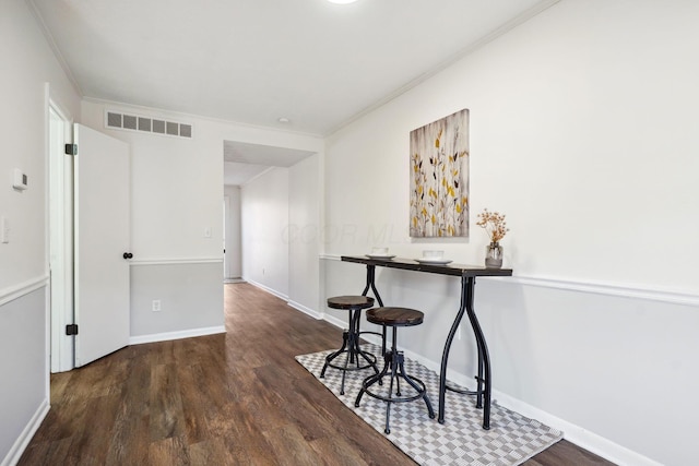 dining room featuring dark wood-style floors, visible vents, crown molding, and baseboards