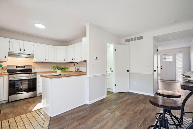 kitchen featuring electric range, visible vents, white cabinets, under cabinet range hood, and butcher block countertops