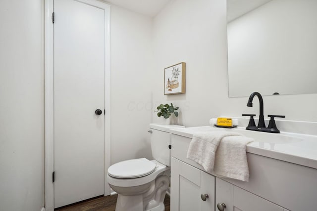 bathroom with toilet, wood finished floors, and vanity