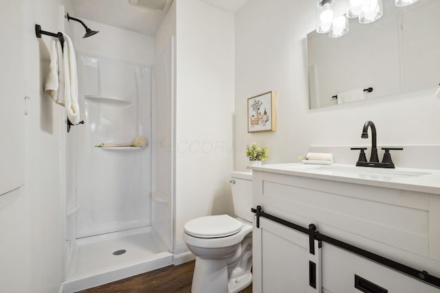 bathroom featuring vanity, a shower stall, wood finished floors, and toilet