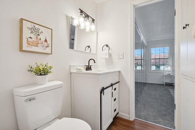 bathroom with wood finished floors, baseboards, toilet, and vanity