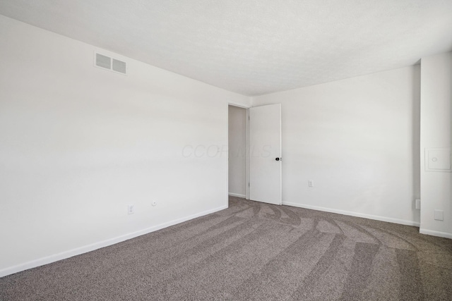 unfurnished room with a textured ceiling, carpet floors, baseboards, and visible vents