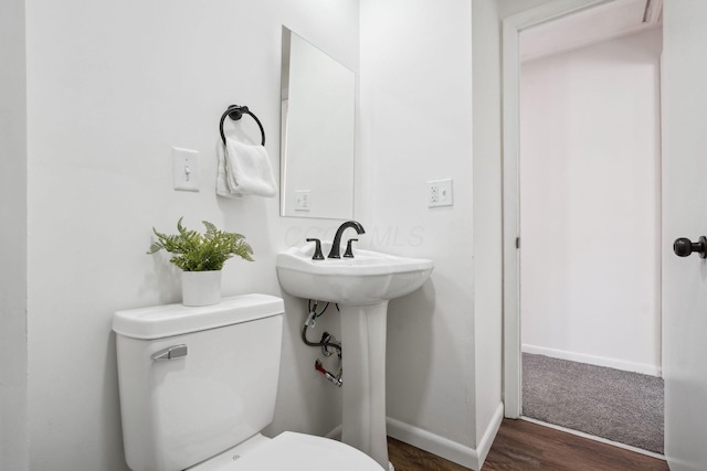 bathroom with wood finished floors, baseboards, toilet, and a sink