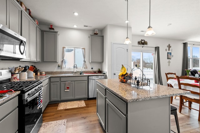 kitchen featuring stainless steel appliances, a center island, gray cabinets, and hanging light fixtures