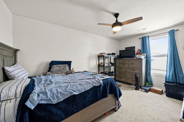 bedroom featuring a textured ceiling, a ceiling fan, light colored carpet, and visible vents