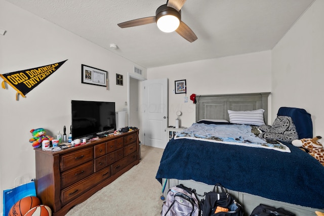 bedroom featuring a textured ceiling, light carpet, a ceiling fan, and visible vents