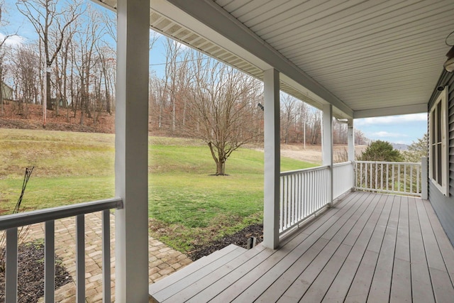 wooden terrace featuring a porch and a yard