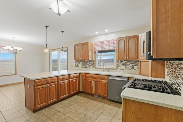 kitchen with sink, dishwasher, hanging light fixtures, decorative backsplash, and kitchen peninsula