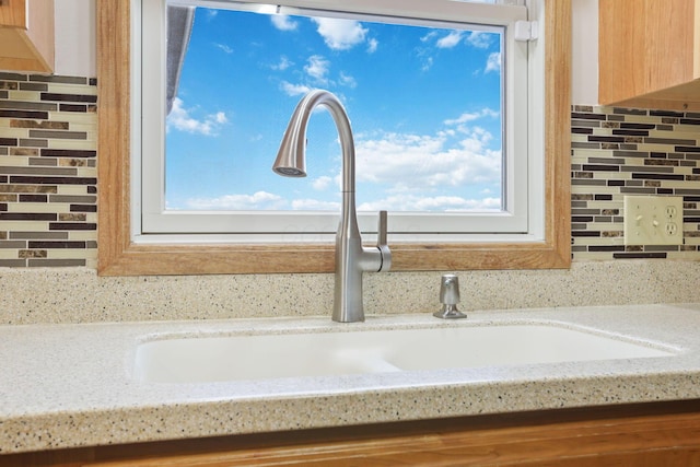 room details with sink, backsplash, and light stone counters