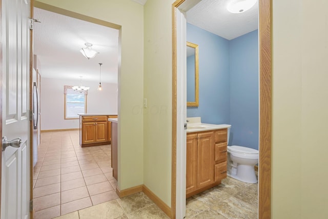 bathroom with toilet, a chandelier, a textured ceiling, vanity, and tile patterned flooring