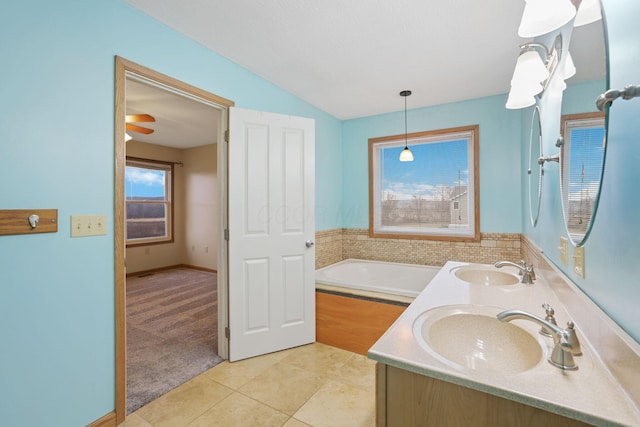 bathroom with a relaxing tiled tub, tile patterned floors, vaulted ceiling, and vanity