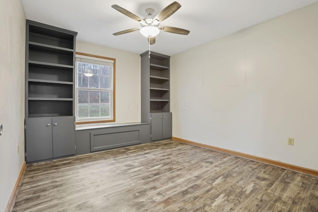 unfurnished room featuring ceiling fan, hardwood / wood-style flooring, and built in shelves