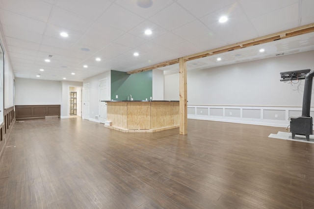 interior space featuring bar, a paneled ceiling, dark hardwood / wood-style floors, and a wood stove