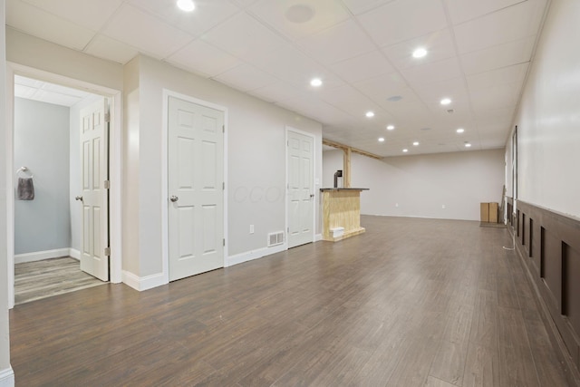 unfurnished living room featuring dark wood-type flooring and a paneled ceiling