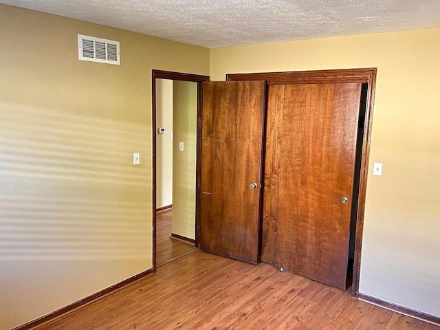 unfurnished bedroom with a closet, a textured ceiling, and light hardwood / wood-style flooring