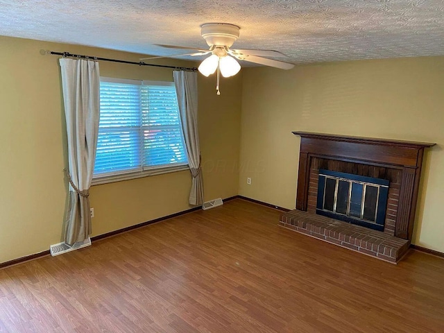 unfurnished living room with a brick fireplace, wood-type flooring, and a textured ceiling