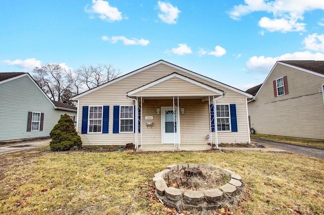 bungalow-style house featuring a front yard, covered porch, and an outdoor fire pit