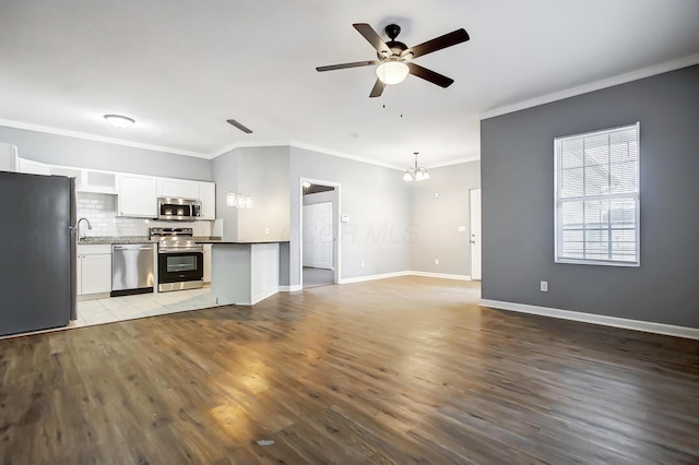 kitchen with light wood-style flooring, appliances with stainless steel finishes, open floor plan, and white cabinetry