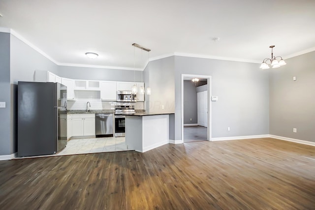 kitchen with light wood finished floors, dark countertops, stainless steel appliances, white cabinetry, and a sink