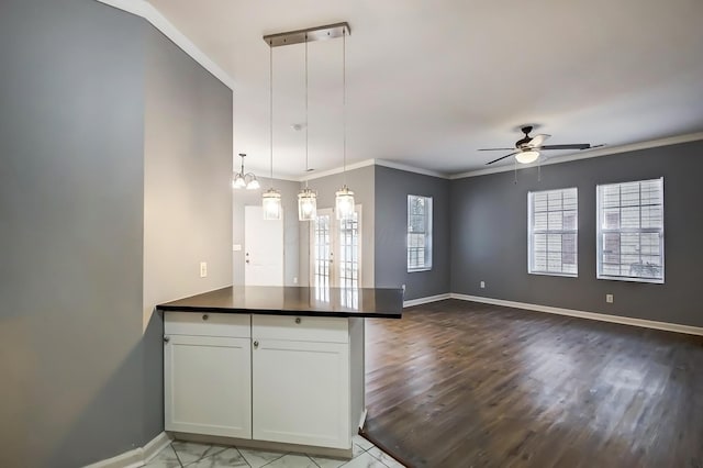 kitchen with baseboards, a peninsula, ornamental molding, dark countertops, and open floor plan