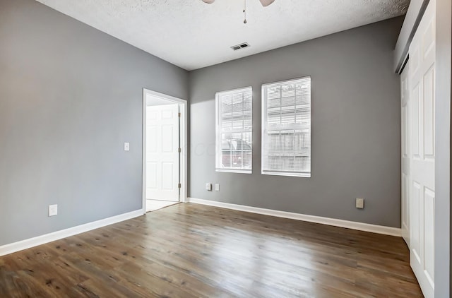 unfurnished bedroom with a textured ceiling, wood finished floors, visible vents, and baseboards