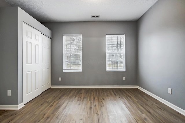 unfurnished bedroom featuring visible vents, dark wood-type flooring, and baseboards