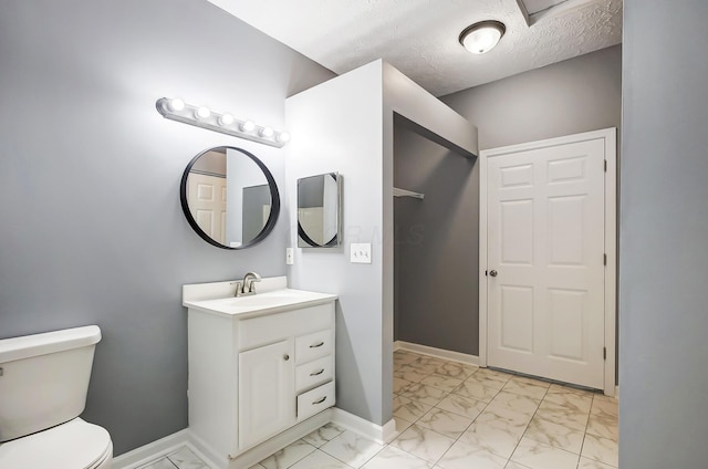 bathroom with baseboards, toilet, vanity, marble finish floor, and a textured ceiling