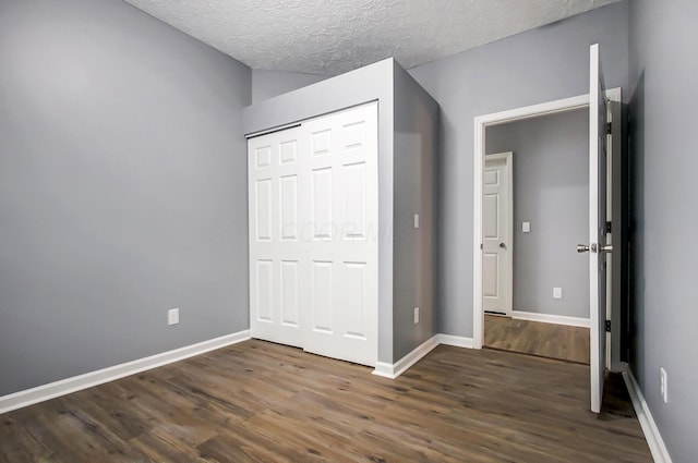 unfurnished bedroom featuring a closet, a textured ceiling, baseboards, and wood finished floors