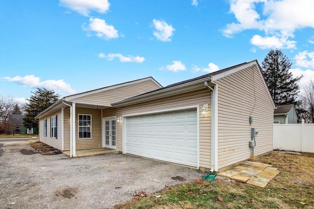 exterior space with an attached garage, gravel driveway, and fence