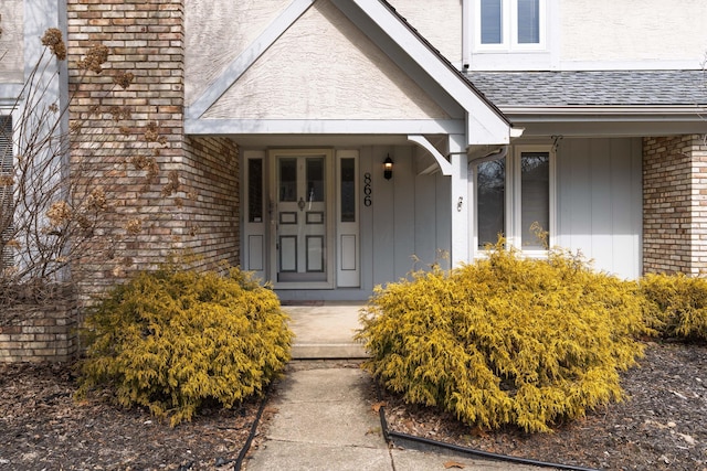 view of exterior entry with roof with shingles