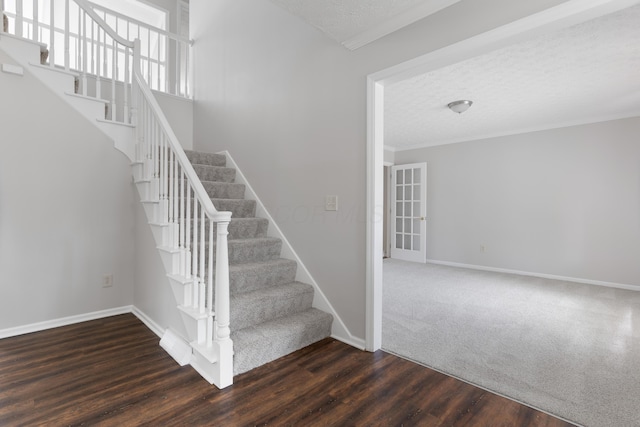 stairs with a textured ceiling, baseboards, and wood finished floors