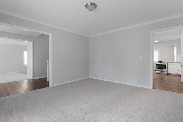 carpeted spare room with baseboards, a textured ceiling, visible vents, and crown molding