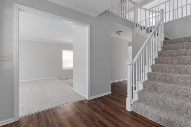 stairs with baseboards, wood finished floors, visible vents, and crown molding