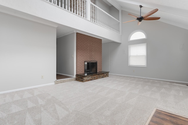 unfurnished living room featuring ceiling fan, high vaulted ceiling, a fireplace, baseboards, and carpet