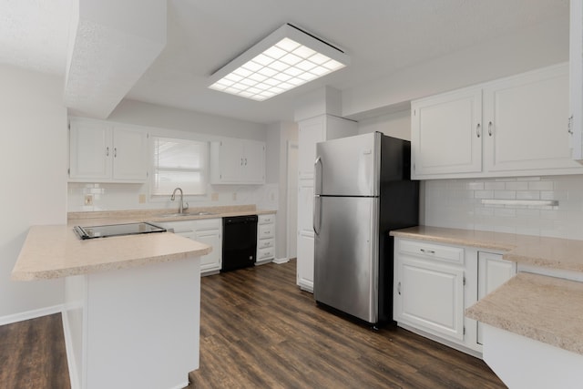 kitchen with freestanding refrigerator, white cabinets, a sink, dishwasher, and a peninsula