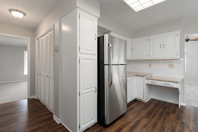 kitchen featuring white cabinets, built in desk, and freestanding refrigerator