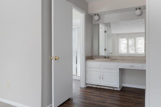 bathroom featuring baseboards, wood finished floors, and vanity