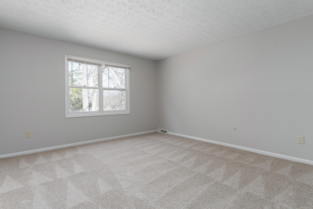 unfurnished room featuring baseboards, visible vents, a textured ceiling, and light colored carpet