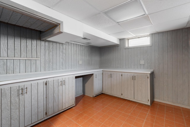 kitchen featuring light countertops, wood walls, and a drop ceiling