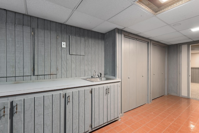 interior space featuring wood walls, a drop ceiling, and a sink