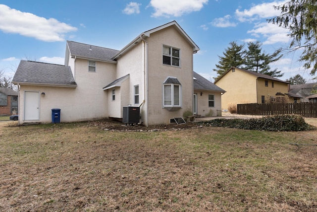 back of property featuring central AC unit, a lawn, roof with shingles, fence, and stucco siding