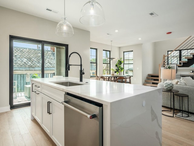 kitchen featuring pendant lighting, sink, white cabinetry, a kitchen island with sink, and stainless steel dishwasher