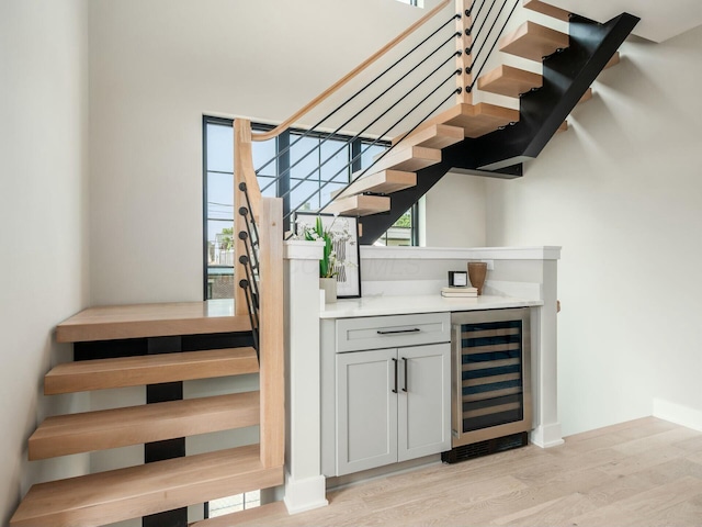 bar with wine cooler, gray cabinets, and light wood-type flooring