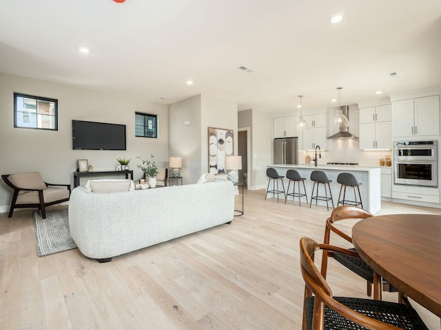 living room featuring sink and light hardwood / wood-style floors