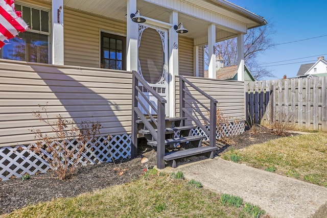 entrance to property with covered porch and fence