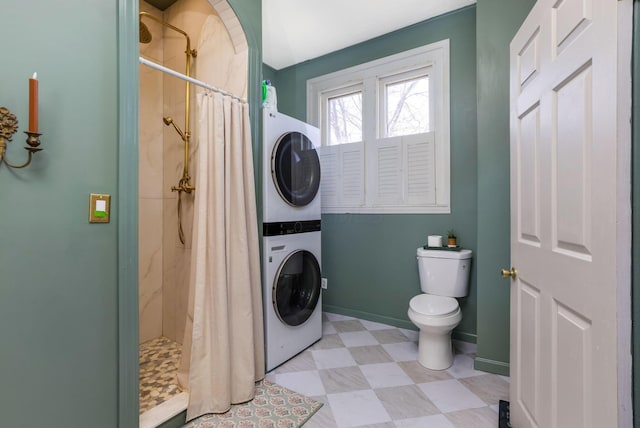 washroom with tile patterned floors, baseboards, laundry area, and stacked washer / dryer