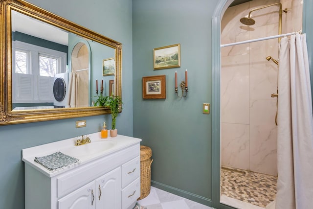 full bath featuring vanity, baseboards, and a tile shower